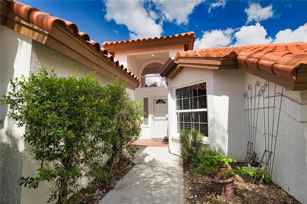 A concrete walkway leads to the white front door of a house with tile roofing — 1191 HARBOR TOWN WAY, VENICE, FL