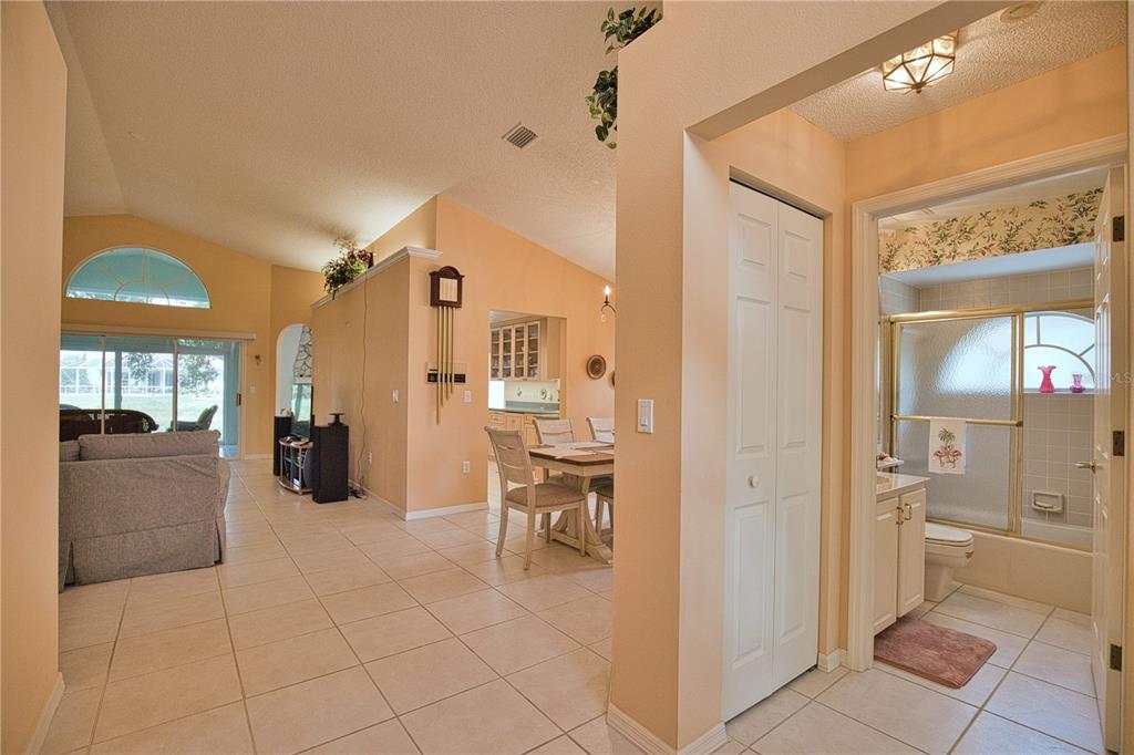 A view from a tiled hallway looking into a living room, dining area, and bathroom — 1191 HARBOR TOWN WAY, VENICE, FL