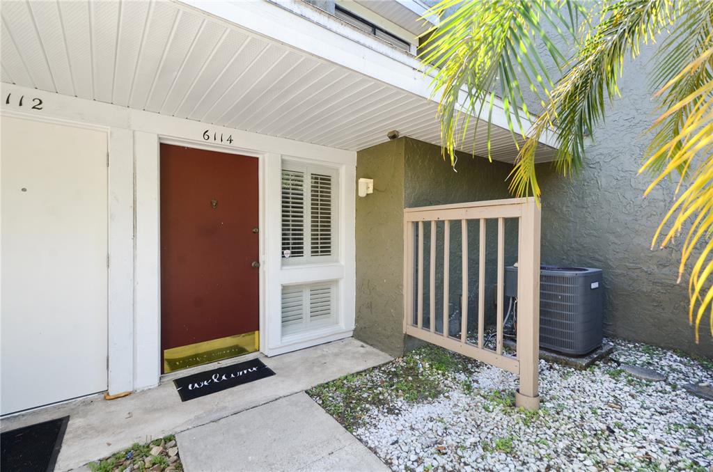 An exterior view of a residential entrance with a red door and an air conditioning unit — 6114 PEREGRINE AVENUE UNIT D03, ORLANDO, FL