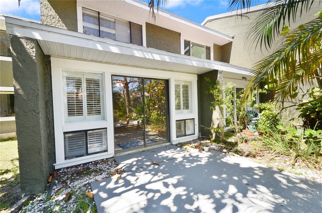 A concrete patio sits in front of a two-story building with sliding glass doors — 6114 PEREGRINE AVENUE UNIT D03, ORLANDO, FL