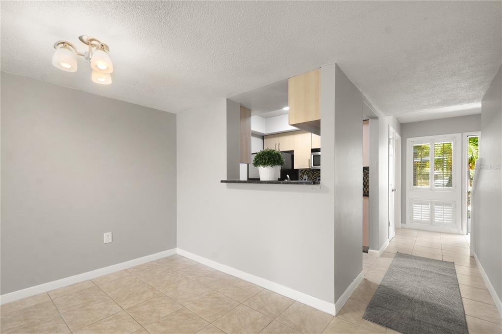 A dining area with tile floors, a pass-through window to the kitchen, and an entryway — 6114 PEREGRINE AVENUE UNIT D03, ORLANDO, FL