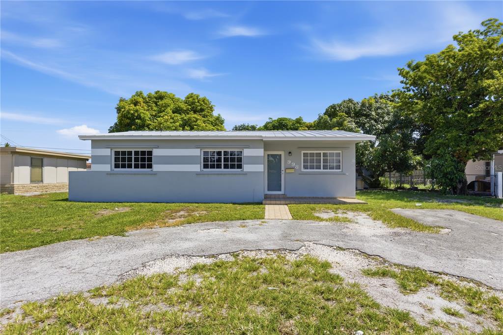 A single-story house with a gray exterior, white horizontal stripes, and a metal roof — 998 W 68TH STREET, HIALEAH, FL