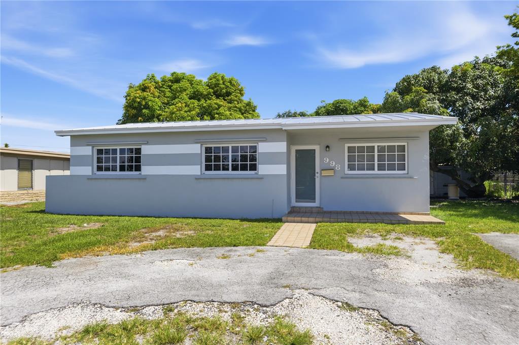 A single-story house with gray and white exterior walls and a metal roof — 998 W 68TH STREET, HIALEAH, FL