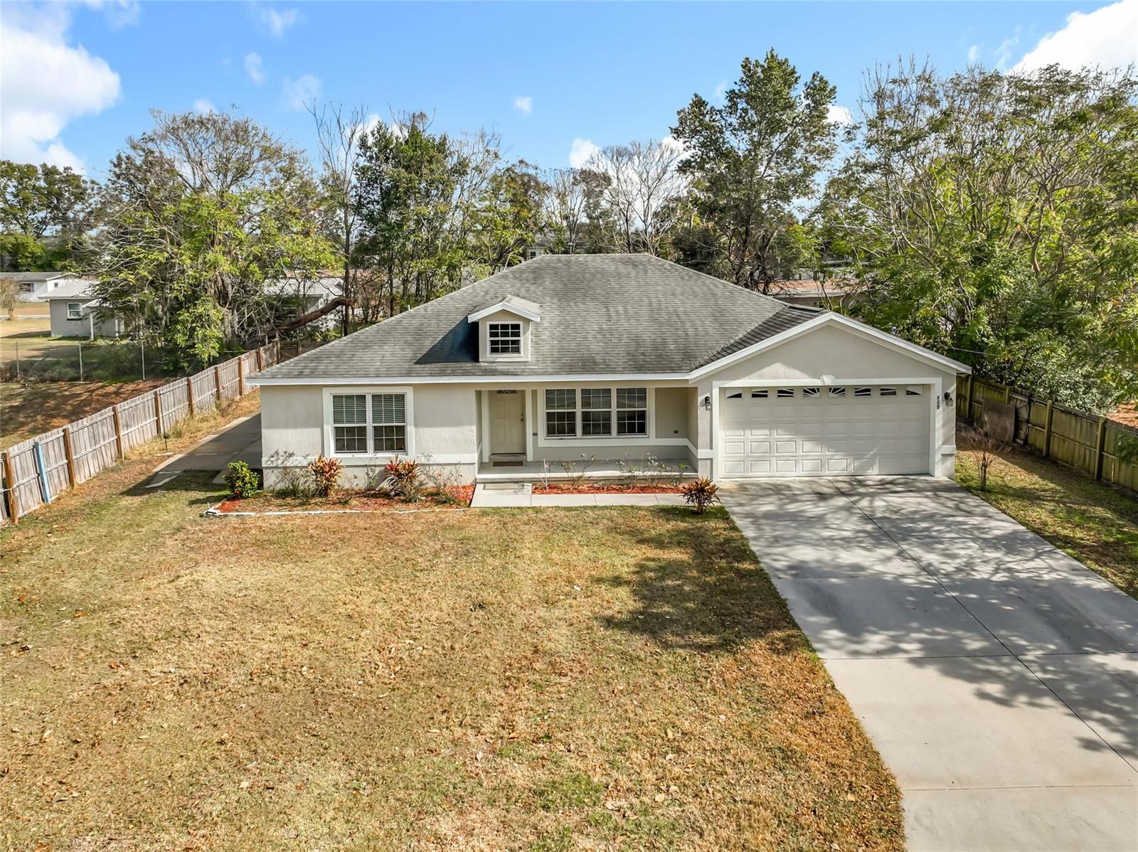 A single-story house with a beige exterior, a two-car garage, and a large front yard — 608 Masters Avenue, Wildwood FL 34785, WILDWOOD, FL