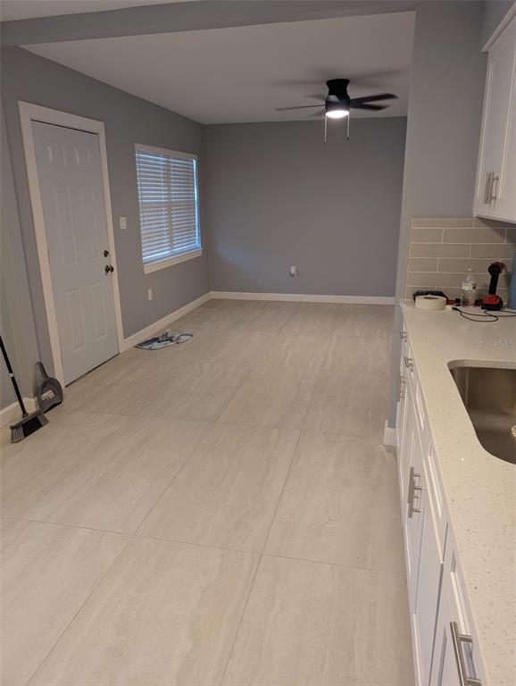 A kitchen area with white cabinets, light countertops, and large-format tile flooring — 4416 N CLARK AVENUE UNIT 4, TAMPA, FL