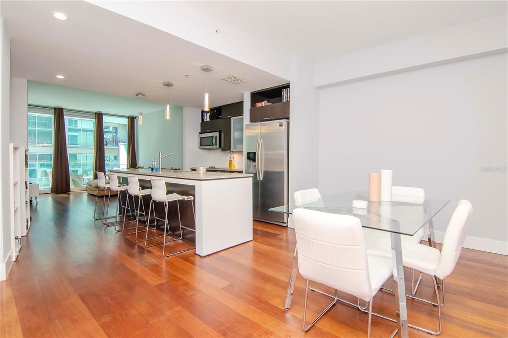 An open-concept kitchen with a breakfast bar and dining area featuring hardwood floors — 111 N 12TH STREET UNIT 1523, TAMPA, FL