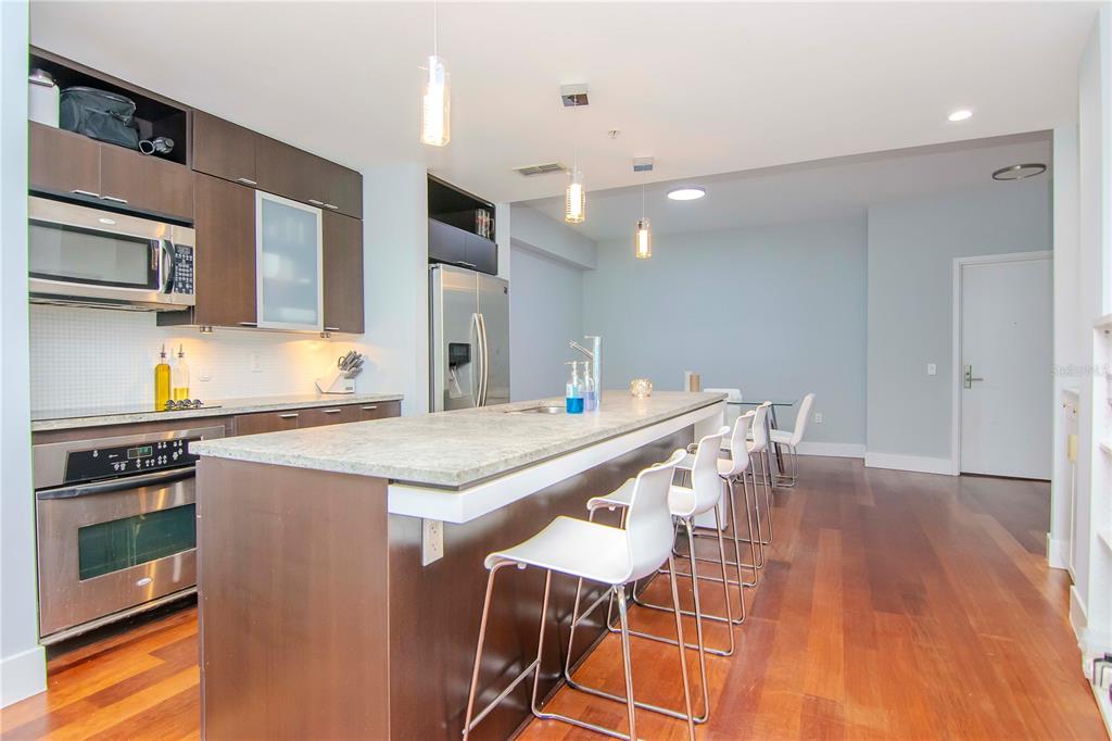 A modern kitchen features dark wood cabinets, stainless steel appliances, and a large stone island — 111 N 12TH STREET UNIT 1523, TAMPA, FL