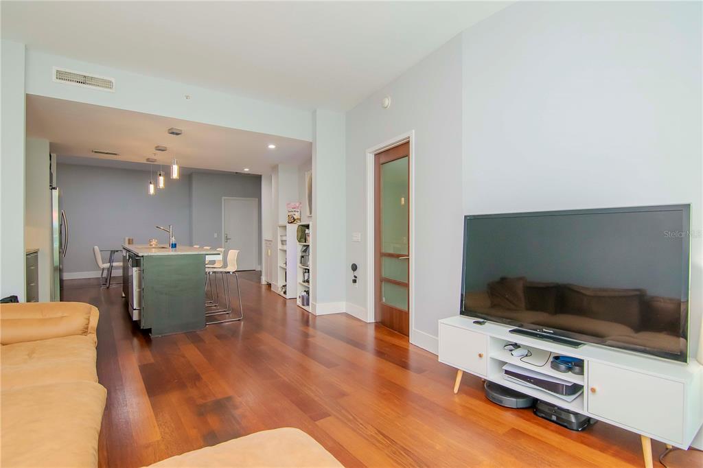 A living room with hardwood floors opens into a kitchen featuring a central island — 111 N 12TH STREET UNIT 1523, TAMPA, FL