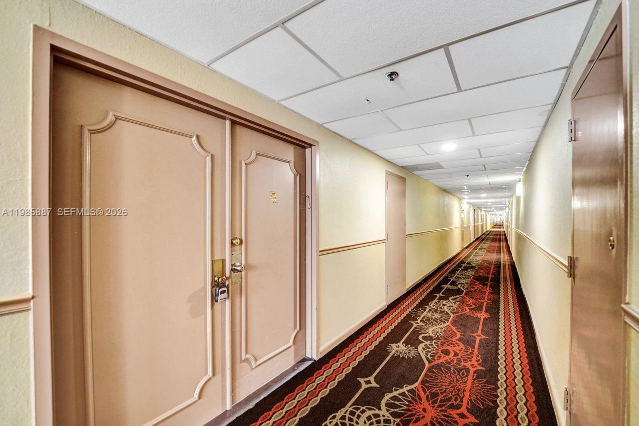 A long hotel hallway features patterned carpet, beige walls, and several closed doors — 4001 Hillcrest Dr # 4, Hollywood FL 33021, HOLLYWOOD, FL