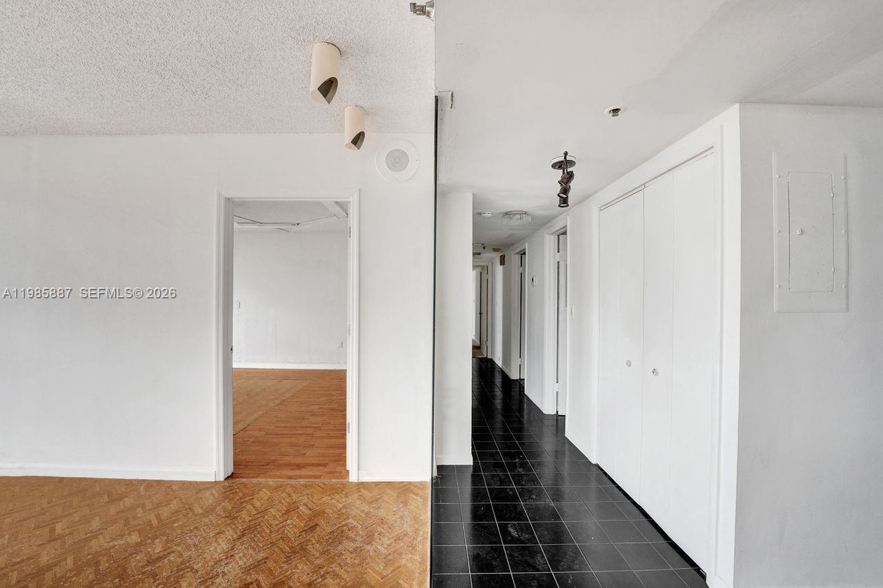 A hallway with black tile flooring leads past white closet doors toward other rooms — 4001 Hillcrest Dr # 4, Hollywood FL 33021, HOLLYWOOD, FL