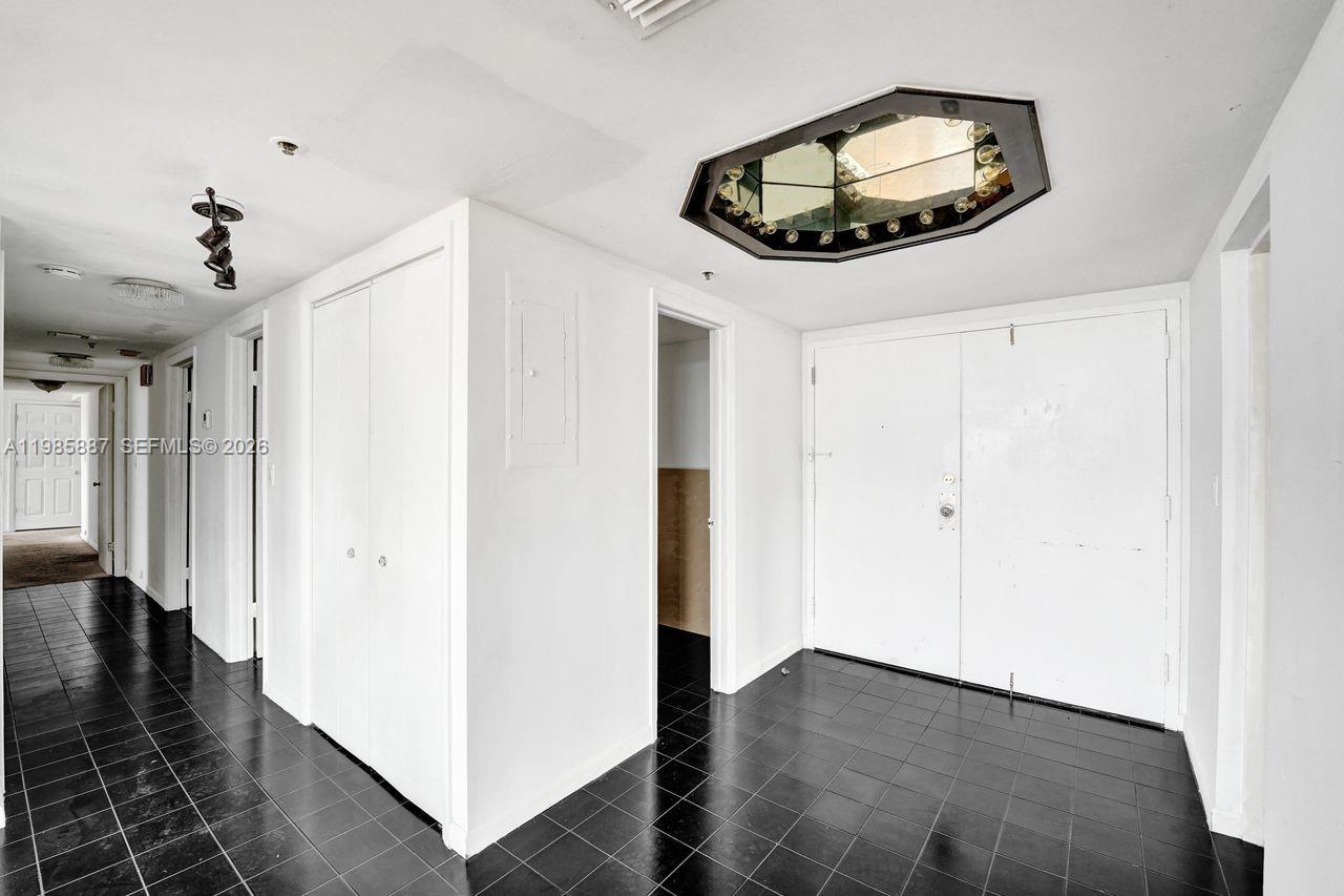 A hallway with black tiled flooring leads to multiple white doors and a mirrored ceiling fixture — 4001 Hillcrest Dr # 4, Hollywood FL 33021, HOLLYWOOD, FL