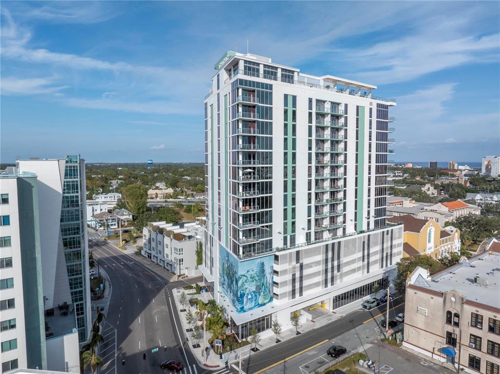 An aerial view of a modern high-rise apartment building featuring a large exterior wall mural — 777 3RD AVENUE N UNIT 708, ST PETERSBURG, FL