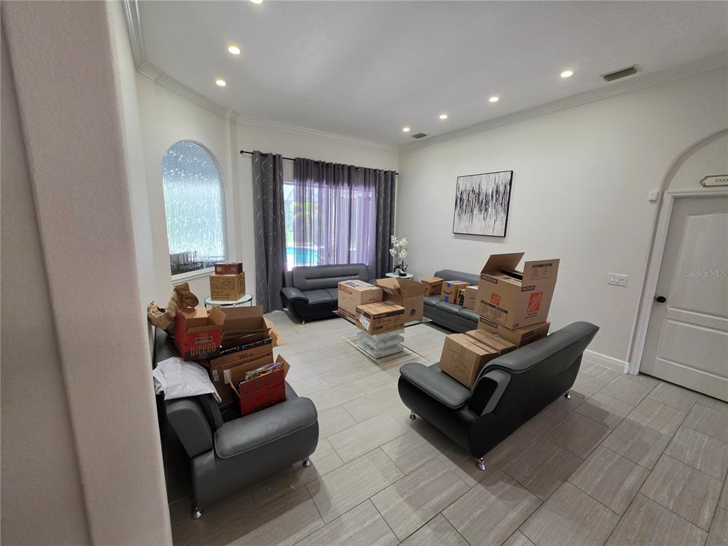 A living room with gray leather furniture, tile flooring, and several cardboard moving boxes — 271 PETREL TRAIL, BRADENTON, FL