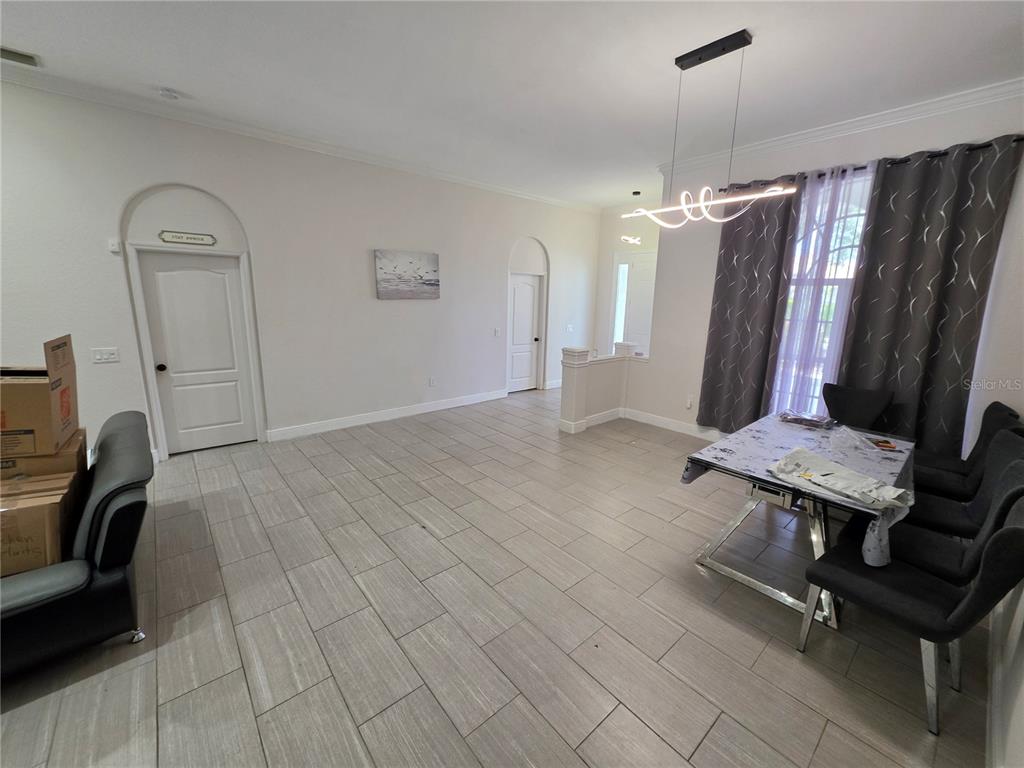 A dining area with light tile floors, a modern light fixture, and dark gray curtains — 271 PETREL TRAIL, BRADENTON, FL