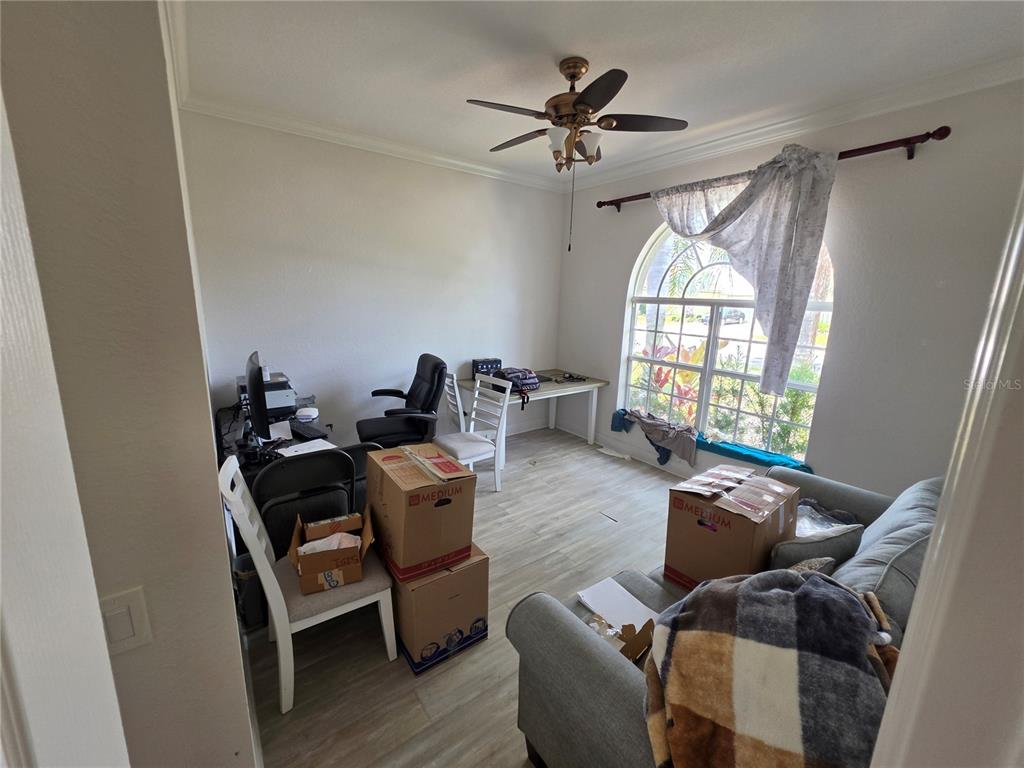 A room with light wood-look flooring, an arched window, a ceiling fan, and moving boxes — 271 PETREL TRAIL, BRADENTON, FL