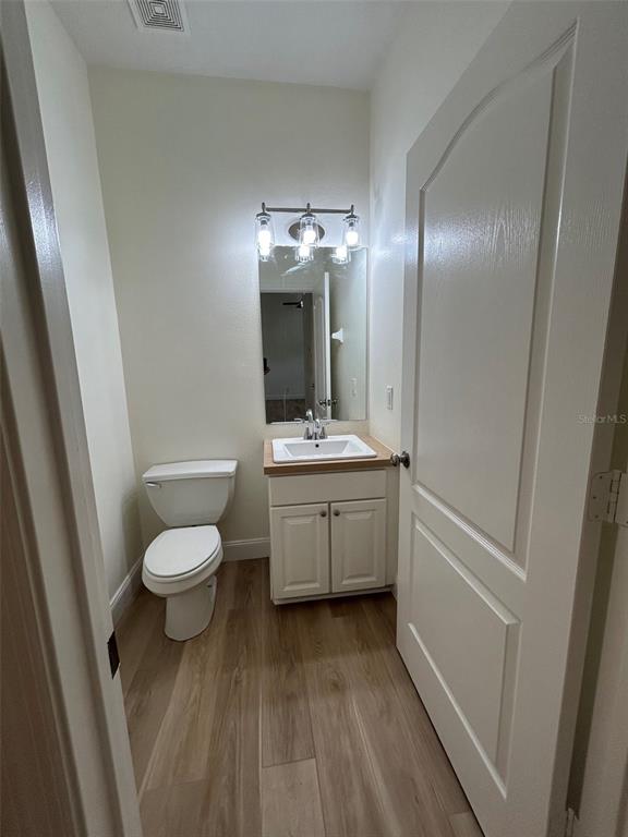 A small bathroom features a white vanity, a toilet, and light wood-look flooring — 34322 TUSCANY AVENUE, SORRENTO, FL