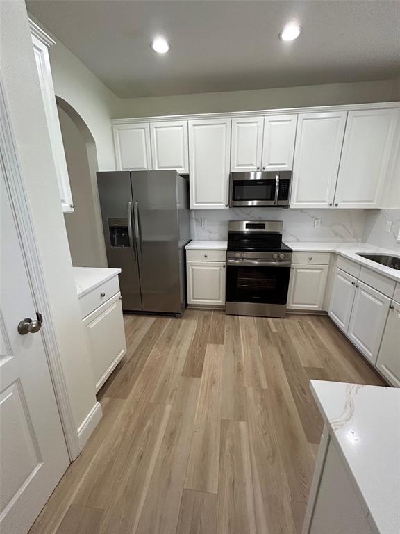 A kitchen features white cabinets, stainless steel appliances, and light wood-look flooring — 34322 TUSCANY AVENUE, SORRENTO, FL