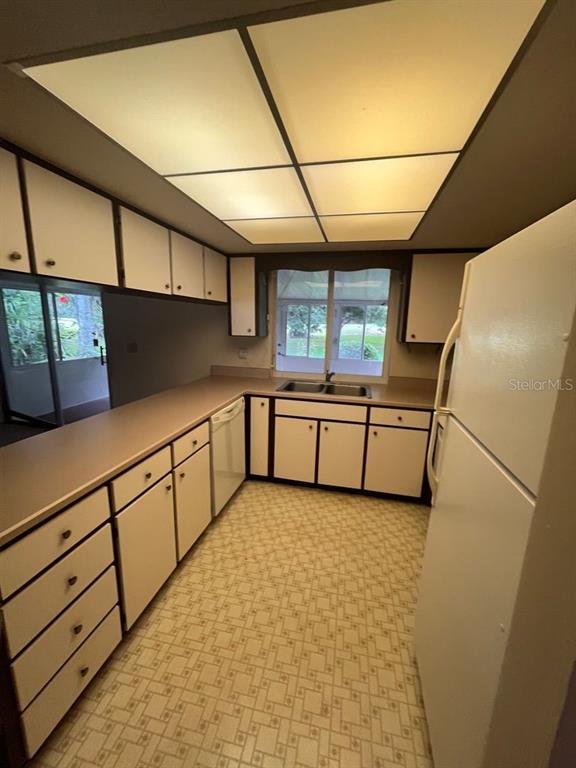 A kitchen features white cabinets, laminate countertops, a drop ceiling, and a patterned vinyl floor — 13 COURTNEY PLACE, PALM COAST, FL