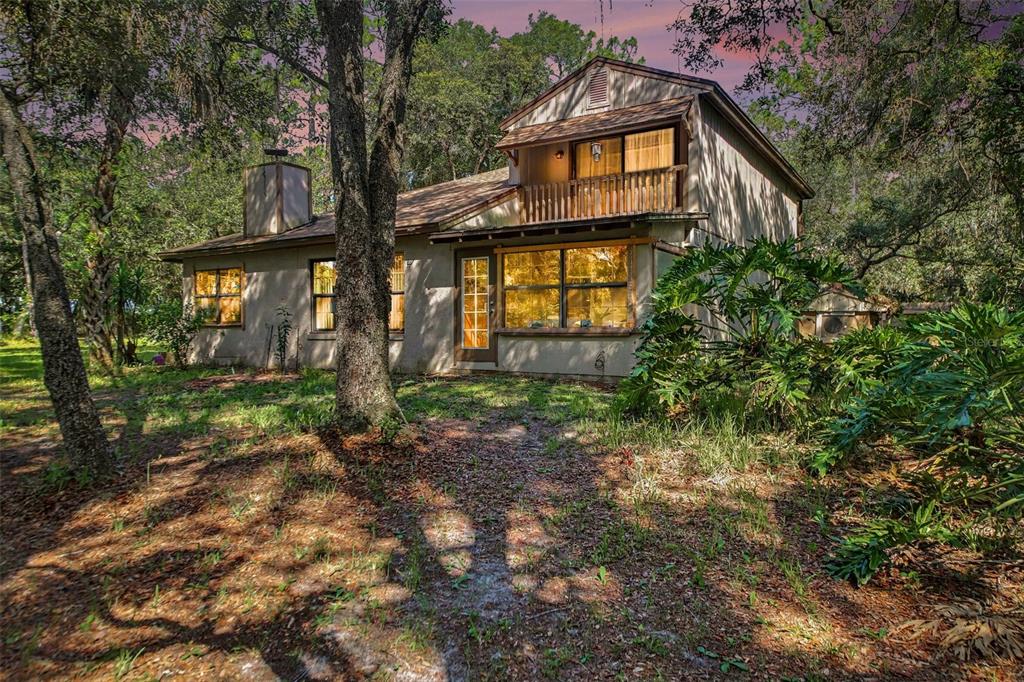 A two-story house with a wooden balcony and large windows sits among mature trees — 284 CLEARVIEW ROAD, OVIEDO, FL