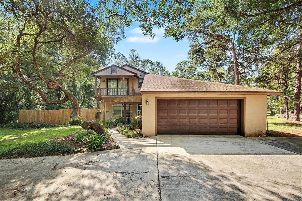 A two-story house with a brown garage, a balcony, and mature trees in the yard — 284 CLEARVIEW ROAD, OVIEDO, FL