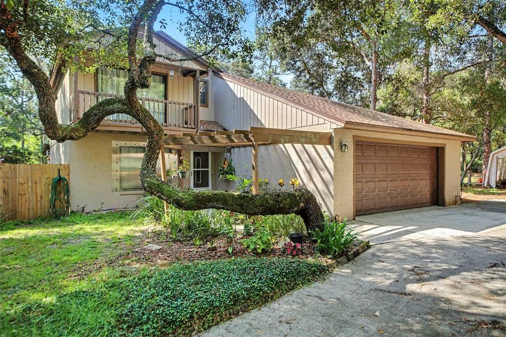 A two-story house with a prominent curved tree in the front yard and a garage — 284 CLEARVIEW ROAD, OVIEDO, FL