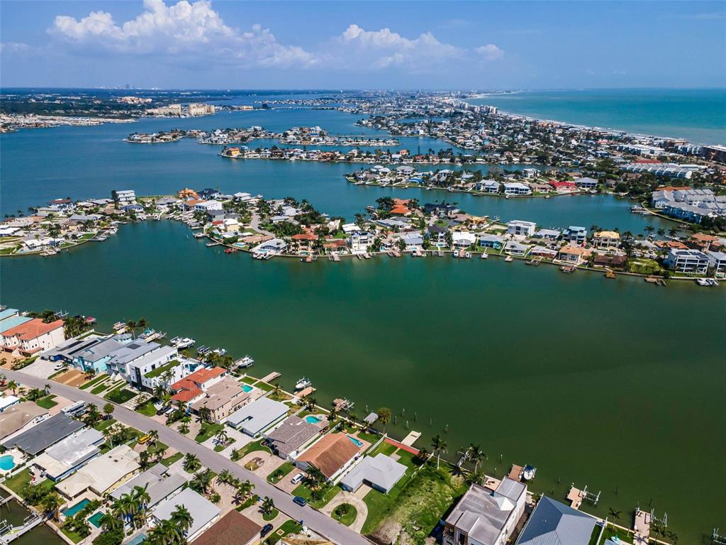 An aerial view shows waterfront homes along a canal with boats docked at private piers — 17043 DOLPHIN DRIVE, NORTH REDINGTON BEACH, FL