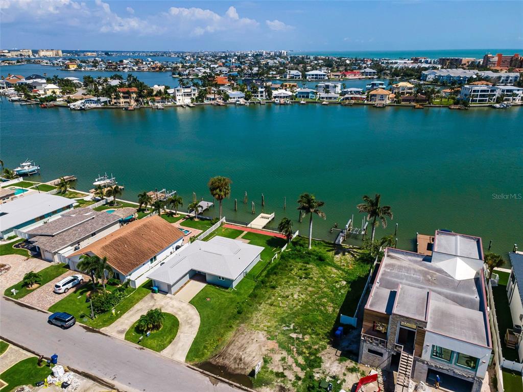 An aerial view shows waterfront homes with docks along a canal near the ocean — 17043 DOLPHIN DRIVE, NORTH REDINGTON BEACH, FL