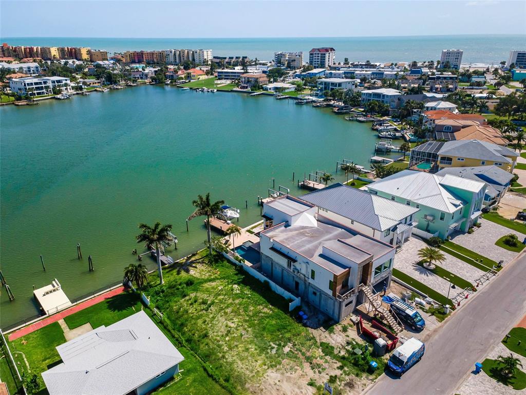An aerial view shows waterfront homes along a bay with docks and boats — 17043 DOLPHIN DRIVE, NORTH REDINGTON BEACH, FL