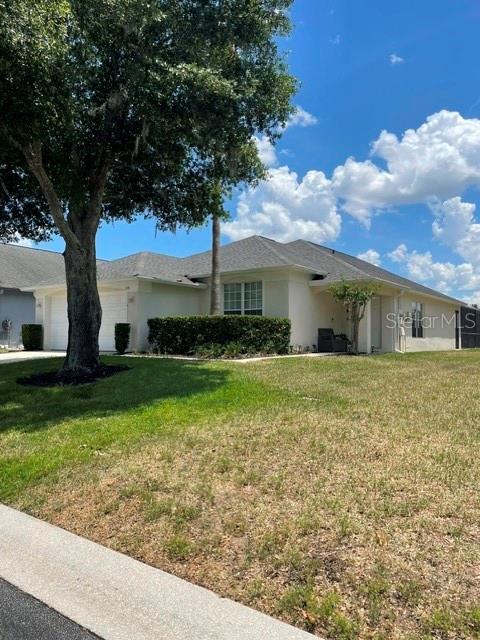 A single-story house with a light-colored exterior and a large tree in the front yard — 1531 CASTERTON CIRCLE, DAVENPORT, FL