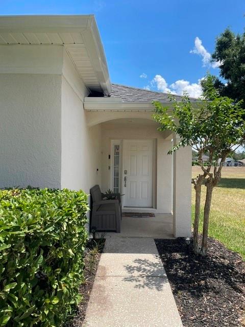 A concrete walkway leads to the front entrance of a house with a covered porch — 1531 CASTERTON CIRCLE, DAVENPORT, FL