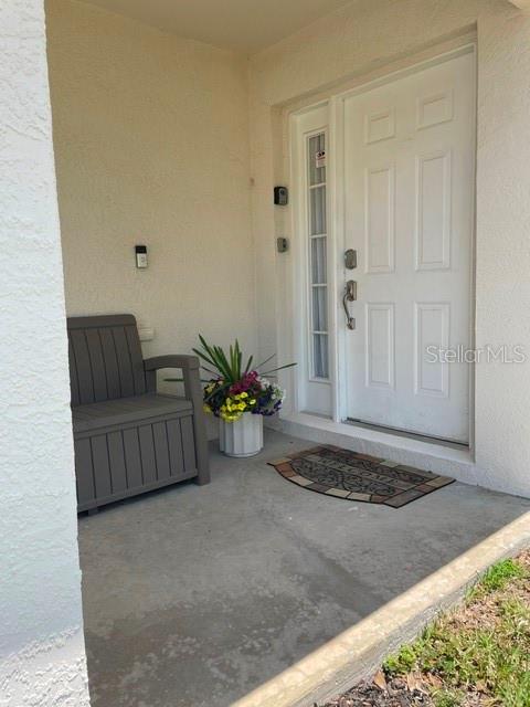 A front porch features a gray storage bench, a potted plant, and a white door — 1531 CASTERTON CIRCLE, DAVENPORT, FL