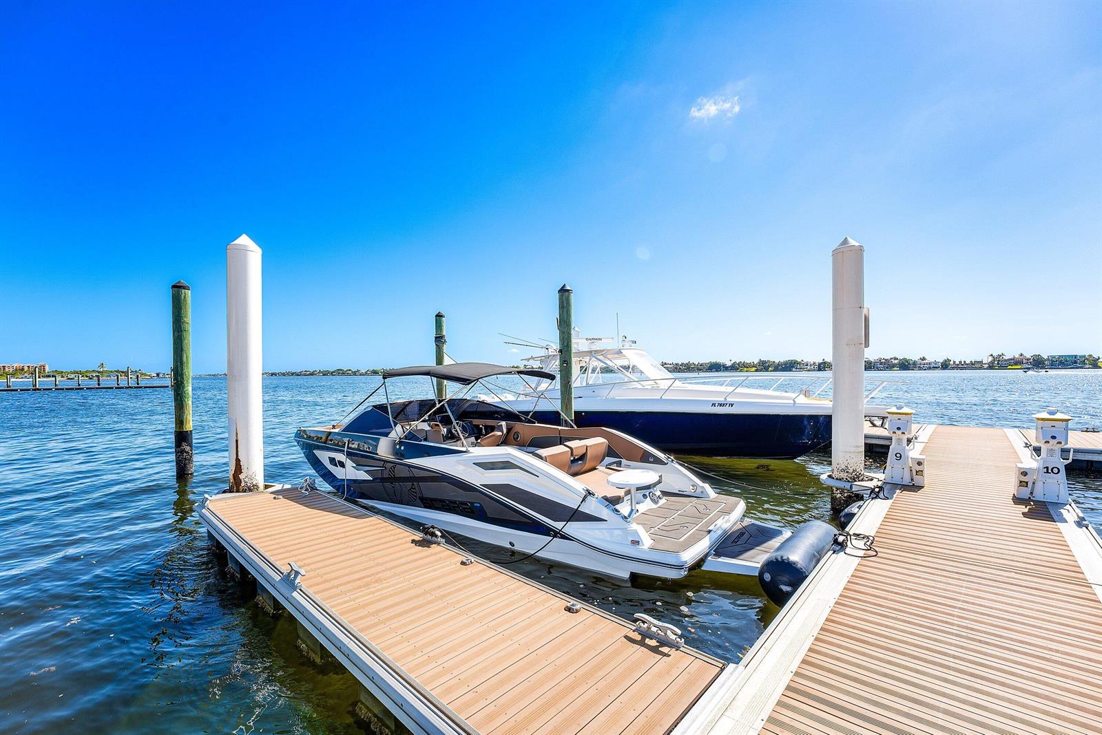 A white and blue motorboat is docked at a wooden pier on a sunny day — 10 Windward Lane, Boynton Beach FL 33435, BOYNTON BEACH, FL