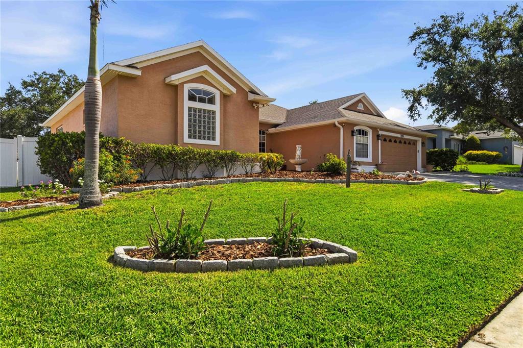 A single-story house with a tan stucco exterior, a two-car garage, and a landscaped lawn — 1085 CHASE DRIVE, WINTER GARDEN, FL
