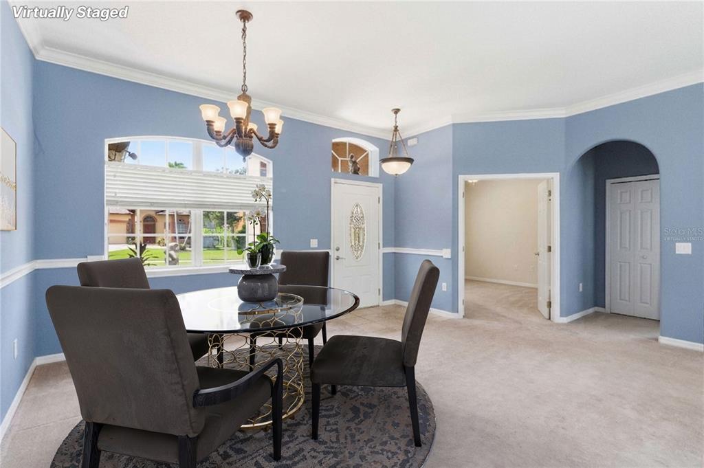 A dining area with blue walls, a glass table, and a chandelier is virtually staged — 1085 CHASE DRIVE, WINTER GARDEN, FL