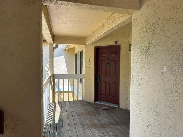 A wooden balcony leads to a red front door marked with the number 324 — 1550 S BELCHER ROAD UNIT 324, CLEARWATER, FL