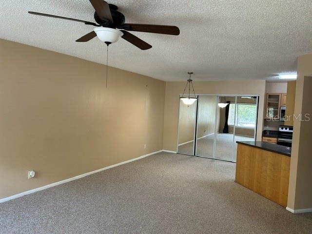 A living room features beige walls, carpeted flooring, a ceiling fan, and mirrored closet doors — 1550 S BELCHER ROAD UNIT 324, CLEARWATER, FL