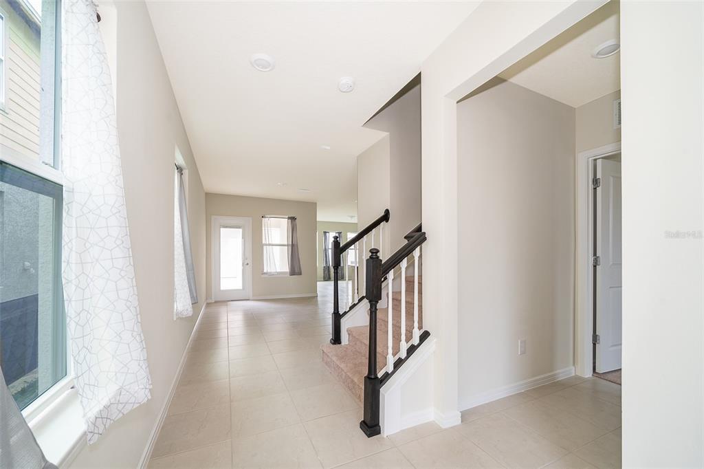 An interior view shows a tiled entryway with a staircase and a hallway leading forward — 1941 SUMMER SERENITY DRIVE, KISSIMMEE, FL