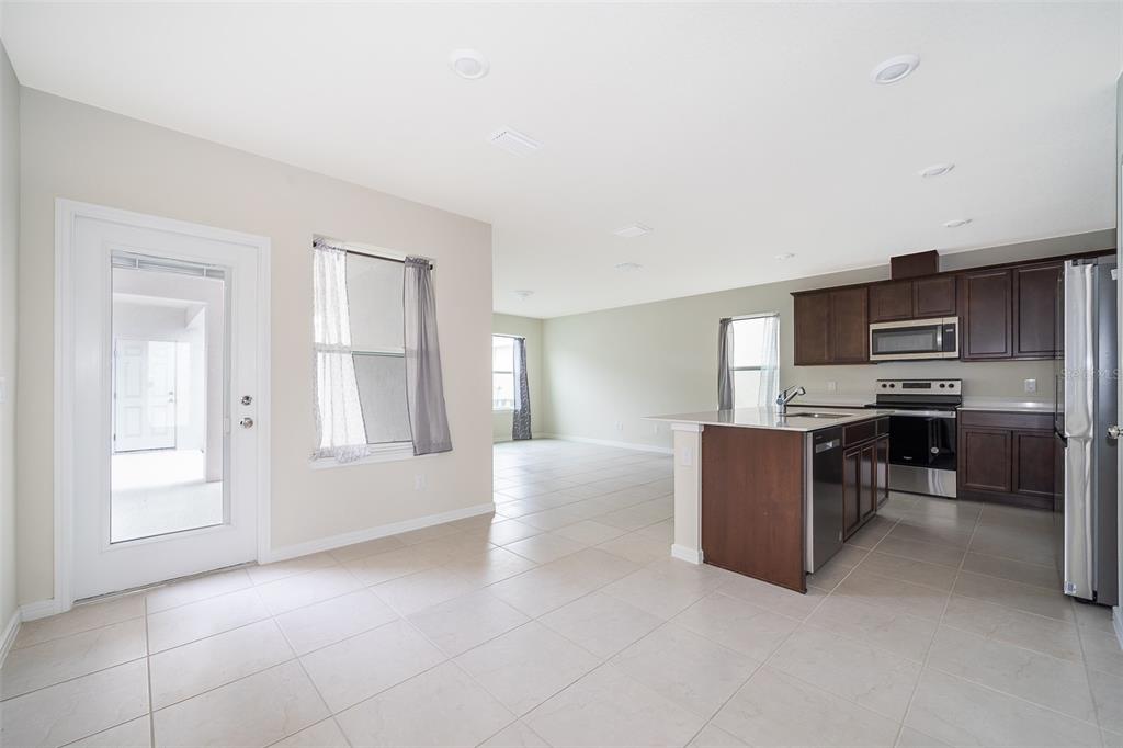 A kitchen with dark wood cabinets and a center island opens into a living area — 1941 SUMMER SERENITY DRIVE, KISSIMMEE, FL