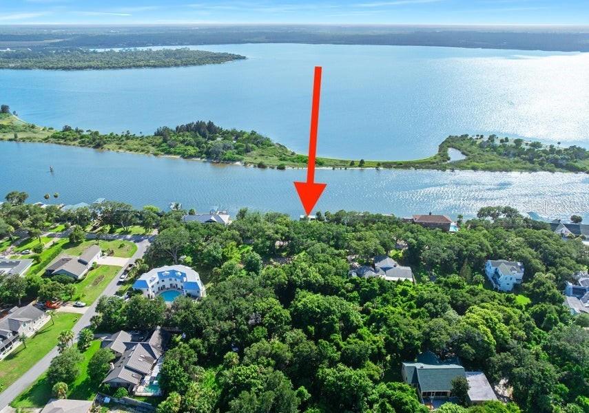 An aerial view shows a wooded waterfront property marked by a red arrow — 2841 JOHN ANDERSON DRIVE, ORMOND BEACH, FL