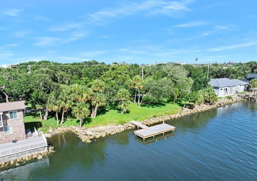 An aerial view shows a waterfront property with a wooden dock and lush green trees — 2841 JOHN ANDERSON DRIVE, ORMOND BEACH, FL