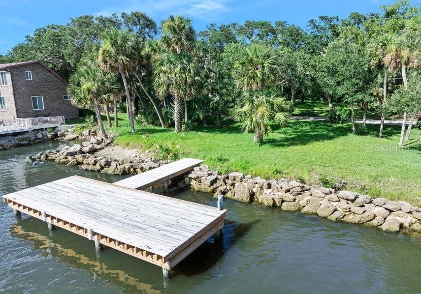 A wooden dock extends into the water next to a grassy yard with palm trees — 2841 JOHN ANDERSON DRIVE, ORMOND BEACH, FL