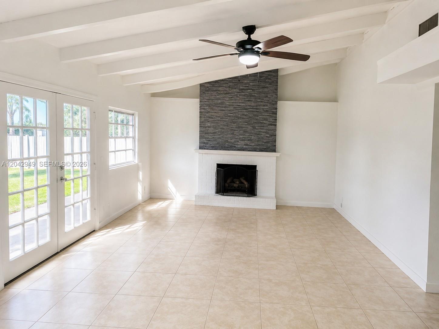 A living room features a stone fireplace, vaulted ceilings with beams, and tile flooring — 401 NW 198th St, Miami Gardens FL 33169, MIAMI GARDENS, FL