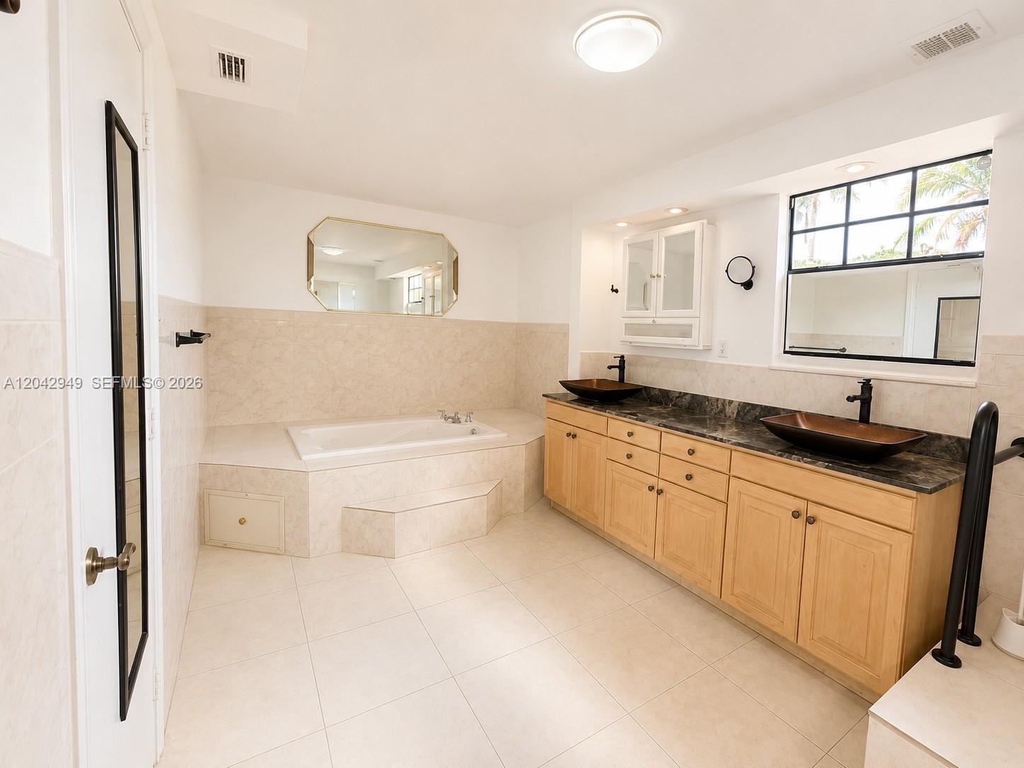 A bathroom features a soaking tub, double vanity with vessel sinks, and light tile flooring — 401 NW 198th St, Miami Gardens FL 33169, MIAMI GARDENS, FL