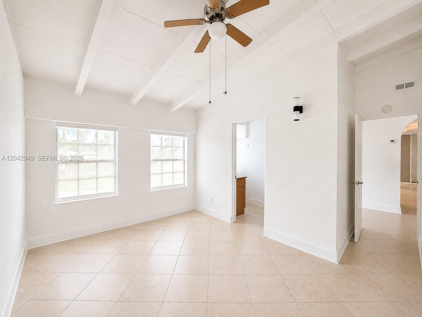 A bright, empty room features white walls, vaulted beamed ceilings, tiled floors, and two windows — 401 NW 198th St, Miami Gardens FL 33169, MIAMI GARDENS, FL