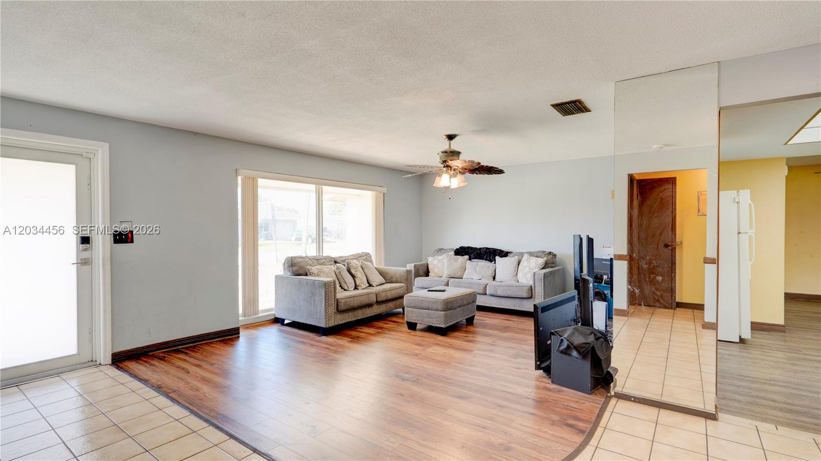 A living room features wood-look flooring, two gray sofas, and a ceiling fan — 6801 NW 25th Ct, Sunrise FL 33313, SUNRISE, FL