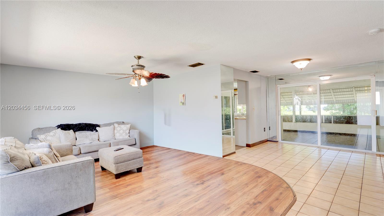 A living room features wood-look flooring, a ceiling fan, and a sliding glass door — 6801 NW 25th Ct, Sunrise FL 33313, SUNRISE, FL