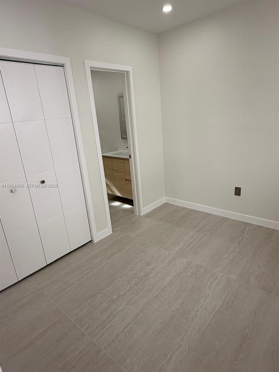 A room with light-colored tile flooring, a white closet, and a doorway to a bathroom — 2436 SW 7th St # 9, Miami FL 33135, MIAMI, FL