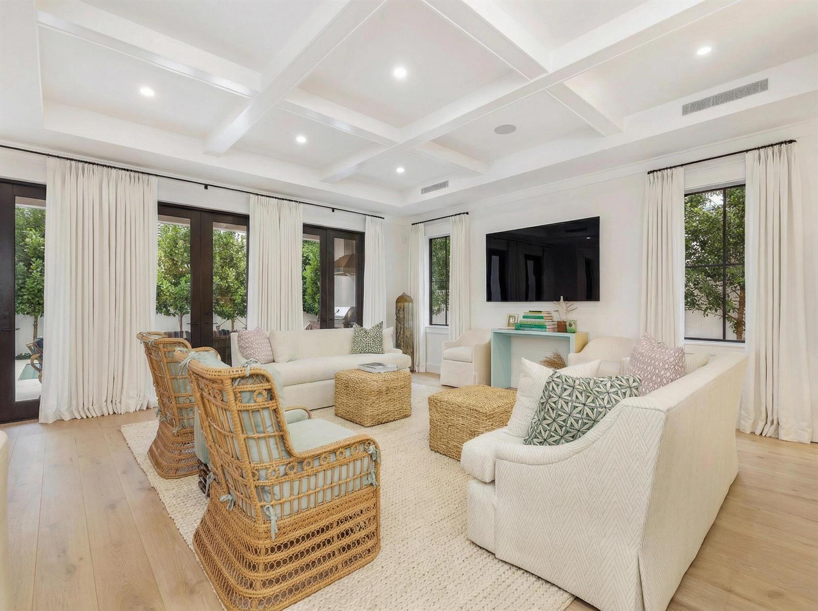A bright living room features a coffered ceiling, wicker armchairs, white sofas, and large windows — 315 Avila Road, West Palm Beach FL 33405, WEST PALM BEACH, FL