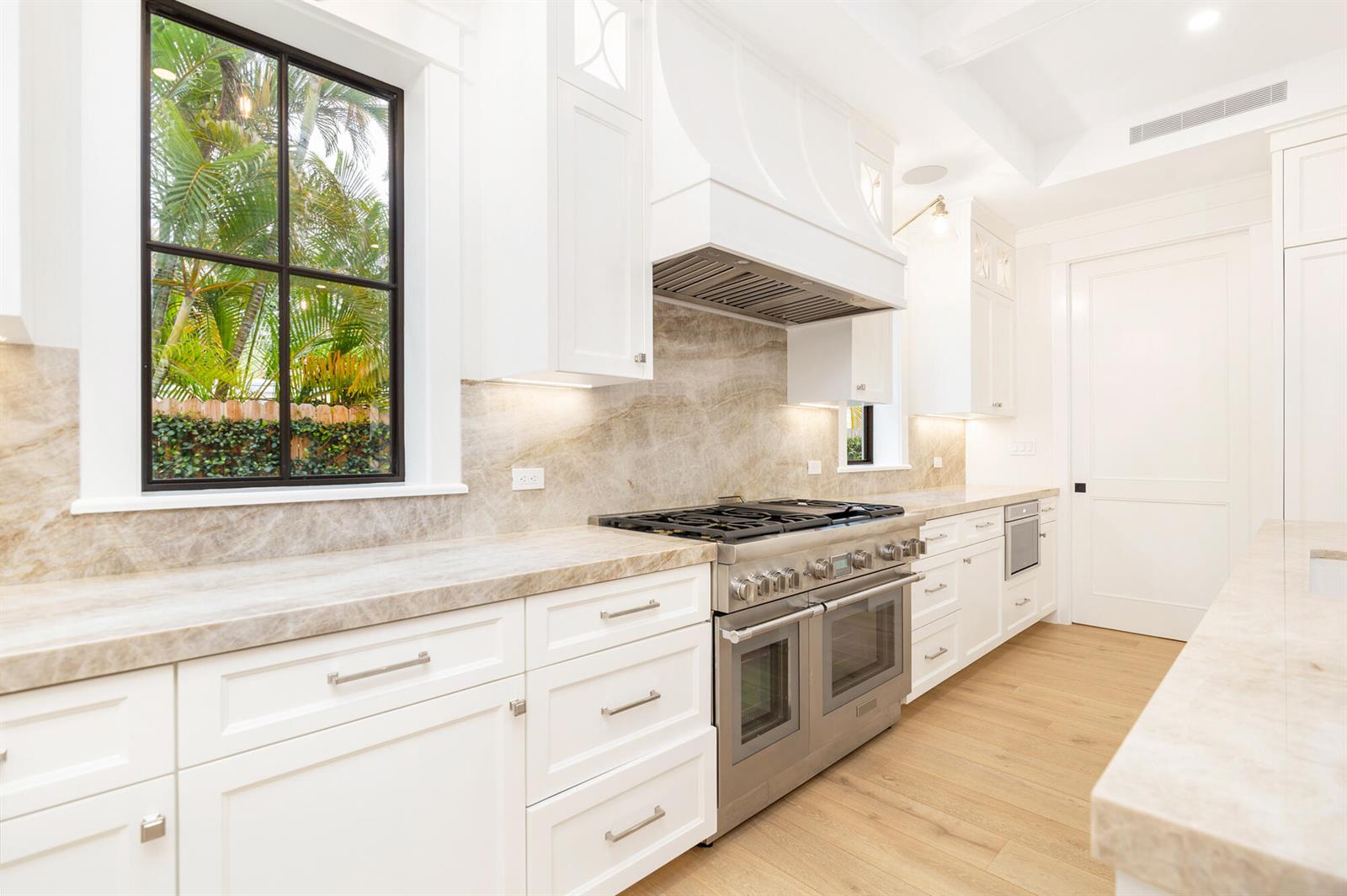 A white kitchen features a stainless steel range, stone countertops, and a large window — 315 Avila Road, West Palm Beach FL 33405, WEST PALM BEACH, FL