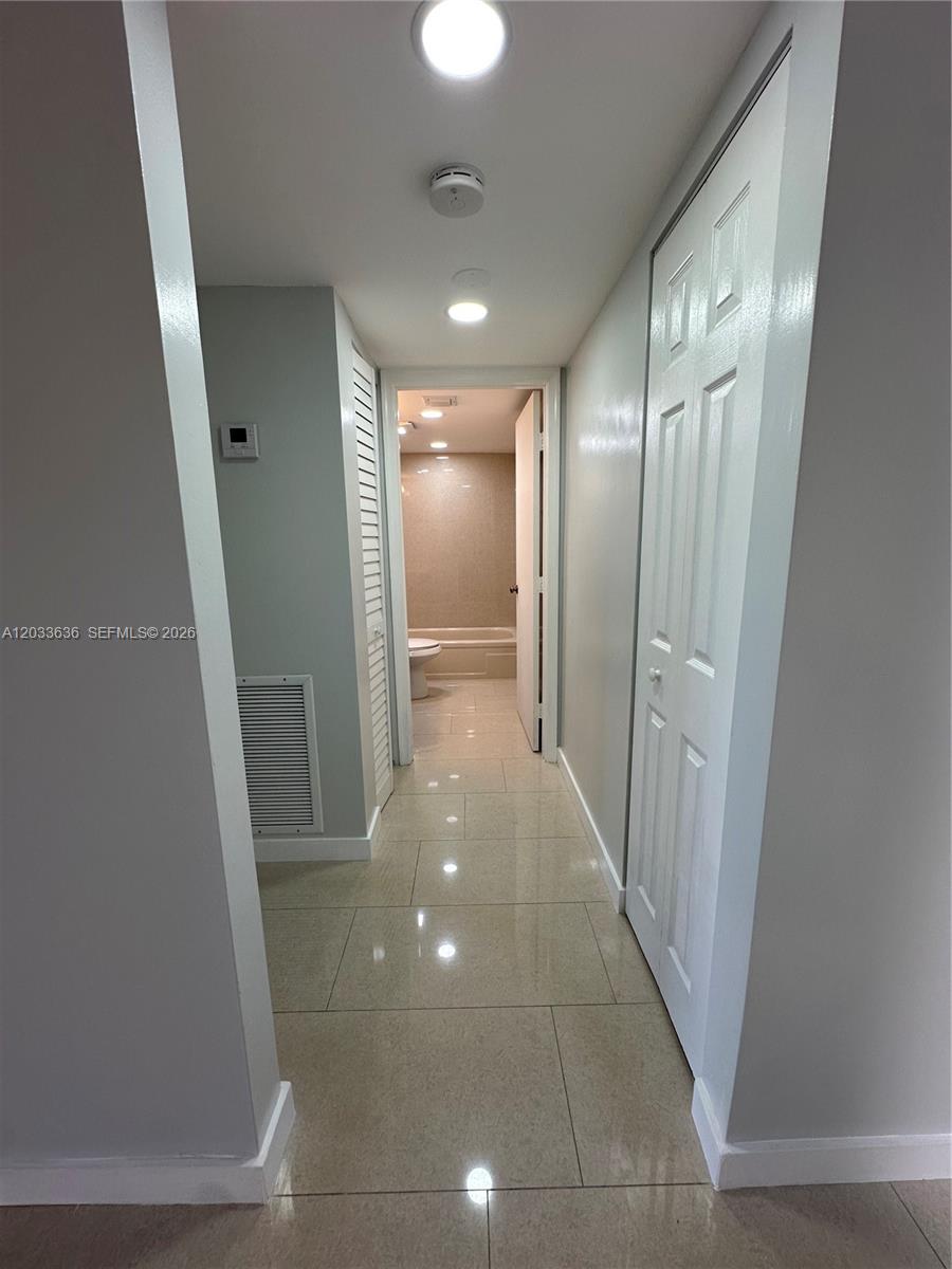 A hallway with tiled floors leads to a bathroom with a tub and toilet — 7561 NW 1st St # 204, Margate FL 33063, MARGATE, FL